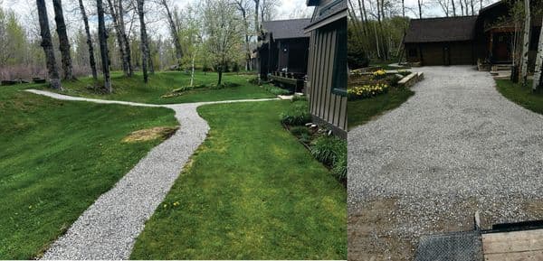 Gravel pathway through green lawn leading to houses in a wooded area.