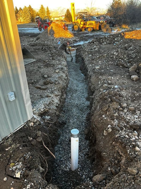 Construction site with a gravel trench and drainage pipe for a building project.