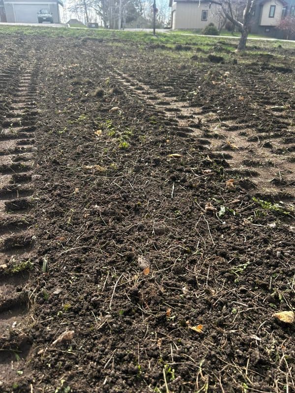 Freshly tilled soil with tire tracks, showing preparation for planting in a rural landscape.